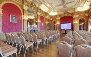 The Banqueting Room set up with theatre style seating. The large TV in the front of the room has the Hylands Estate logo displayed.