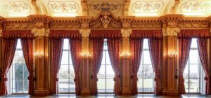 The windows of the Banqueting Room framed with red and gold curtains and candle wall sconces.