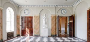 The Entrance Hall of Hylands House. The floors are tiled with black and white and the statue of Venus with the Apple is standing along the wall.