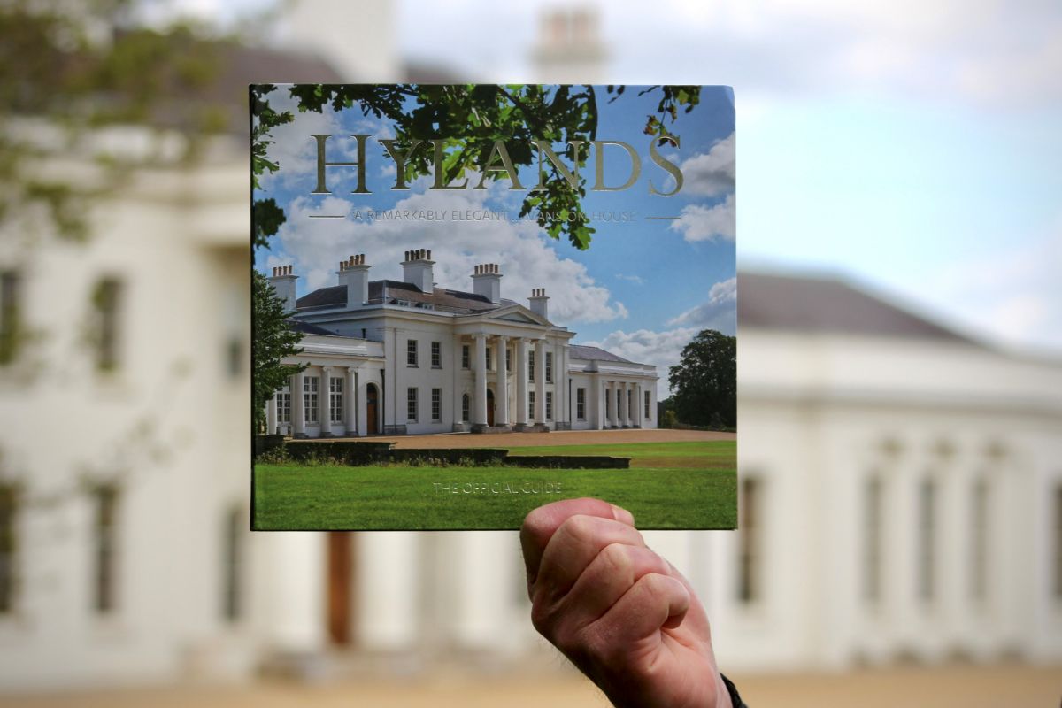 The Hylands official guide book being held up in front of Hylands House.