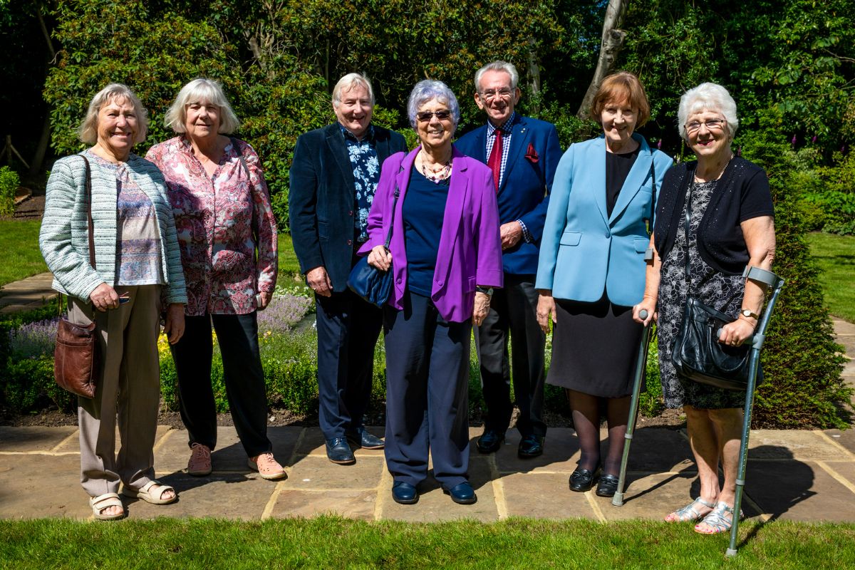 Members of the Friends of Hylands house standing in the Hanbury Memorial Garden smiling at the camera.