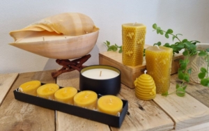 Various candles on a shelf including tealights and beeswax pillar candles.