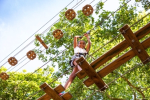 A young girl looking down at the camera while on the tree top course at Go Ape.