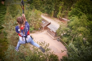 A girl on a zip line through the trees at Go Ape.