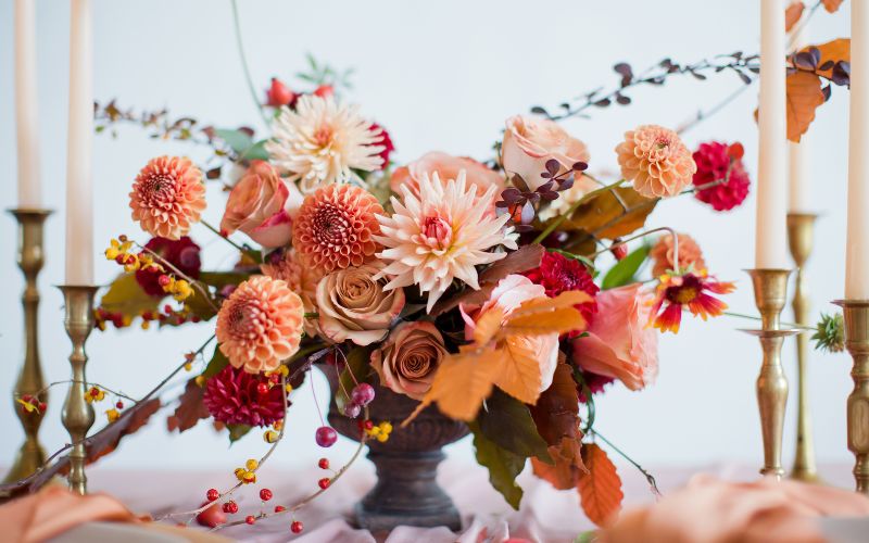 An autumnal wedding centrepiece surrounded by taper candles.