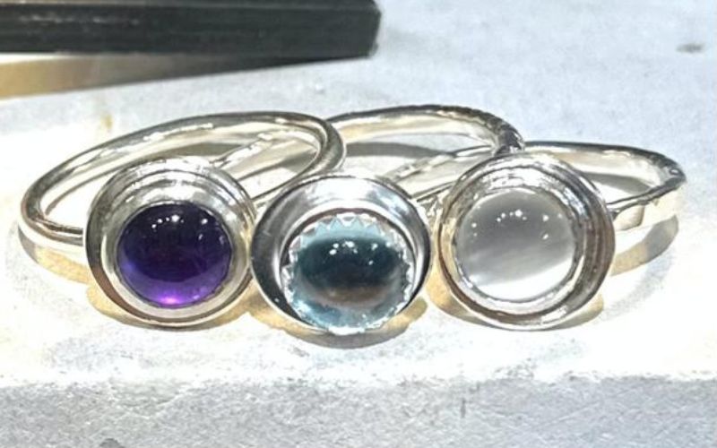 Three silver rings with three different coloured stones.