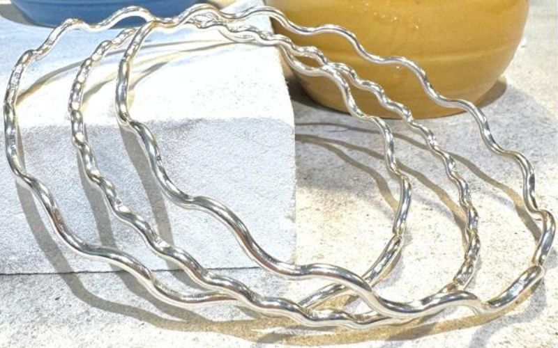 Skinny, wavy silver bangles.