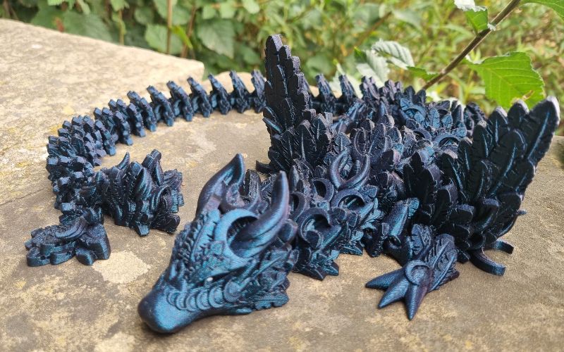 A 3D printed dragon in a shiny blue-black colour.