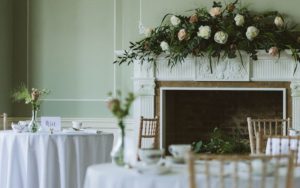 The Terrace Room set for afternoon tea with a large floral display on the fireplace mantle.