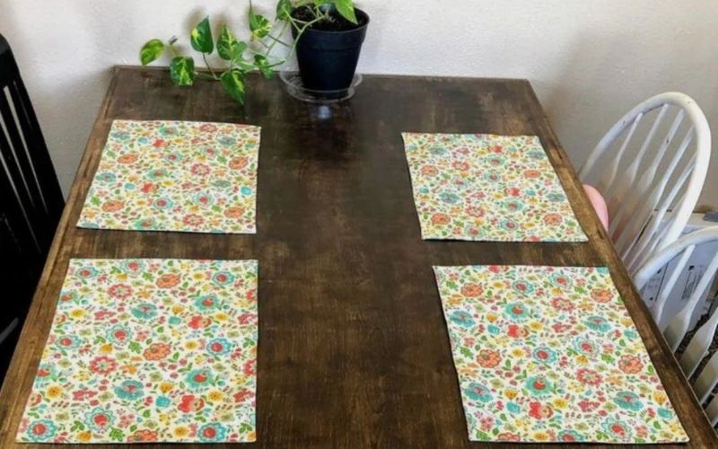 Colourful floral placemats on a wood table.