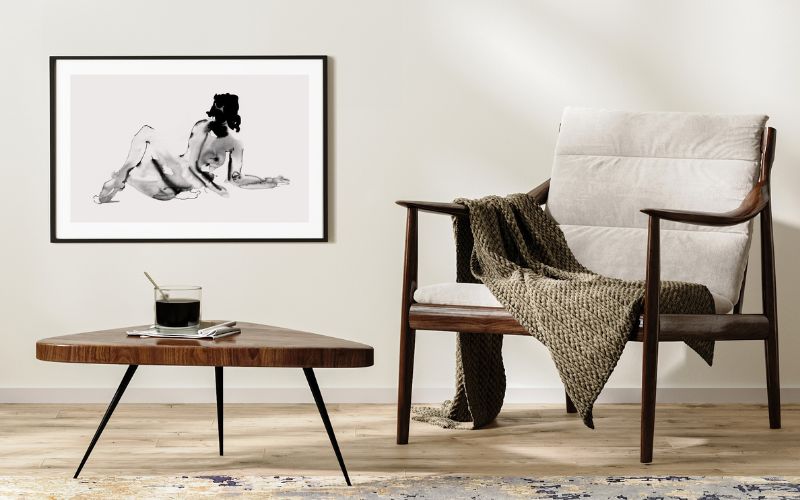 A cosy living room with a chair and coffee table. On the wall is a black and white piece of artwork.