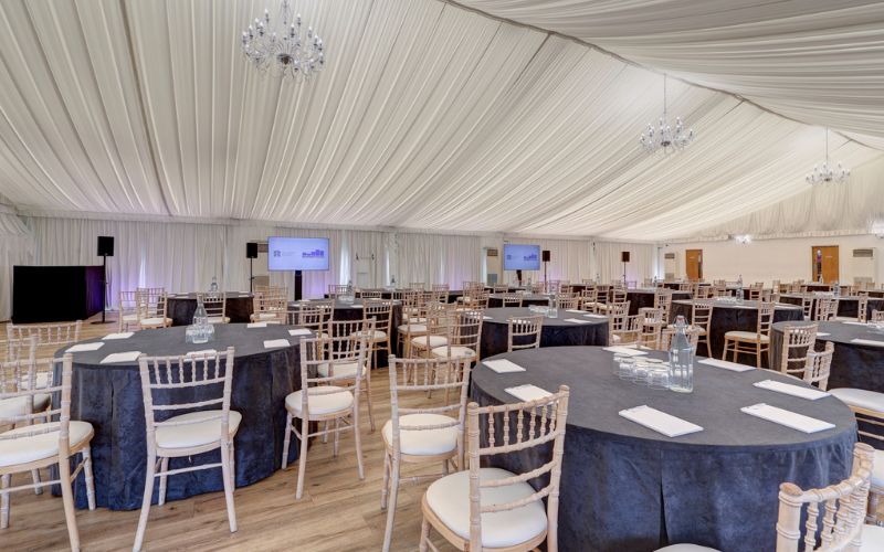 The Grand Pavilion set with round tables and large screens at the front.