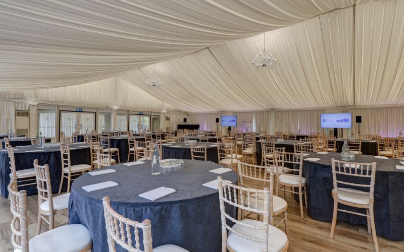 The Grand Pavilion set with round tables and large screens at the front.