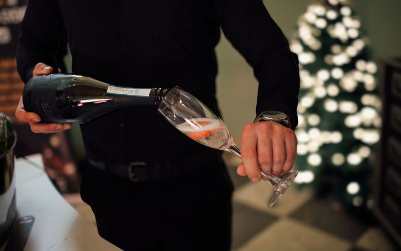 Close up of a man pouring prosecco into a glass.