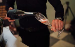 Close up of a man pouring prosecco into a glass.