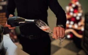 Close up of a man pouring prosecco into a glass.