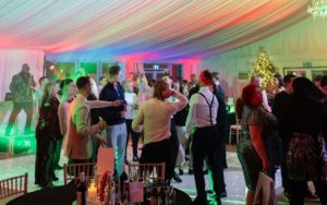 People dancing on a dance floor while a saxophonist plays on stage.