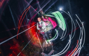 Children walking across a high ropes course at night with fun lighting.